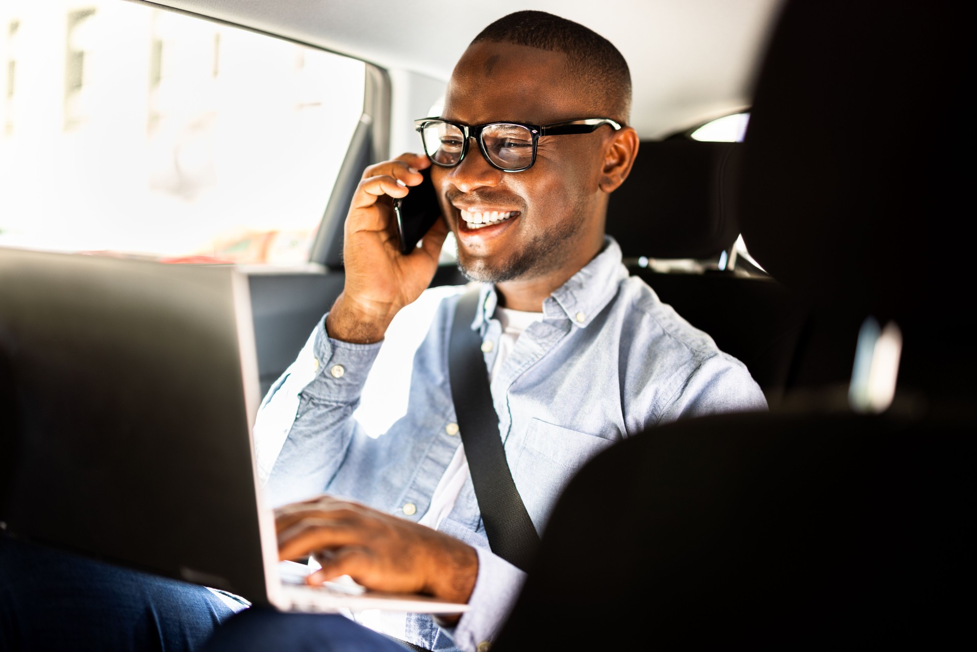 African businessman talking on smartphone while sitting in luxury car